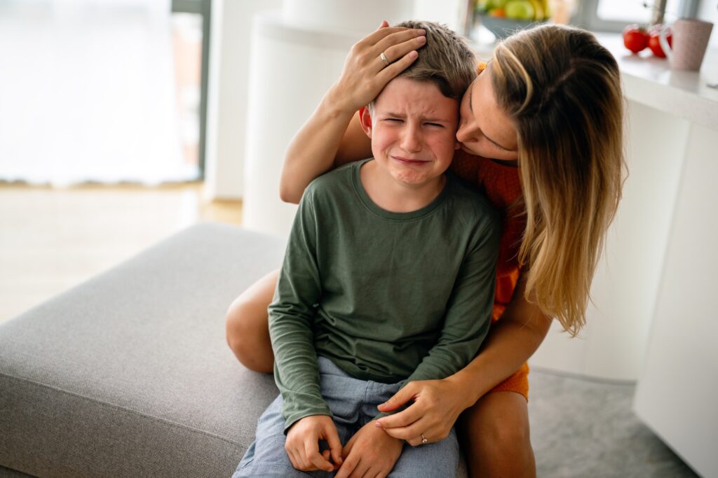 Portrait of mother consoling her crying sad injured son. Child family support parent concept